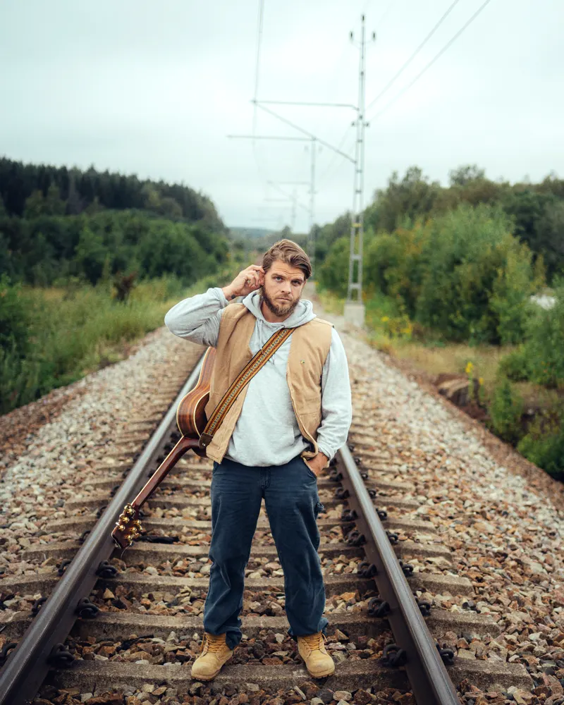 Vincent Jedselius på järnvägsspår med gitarr